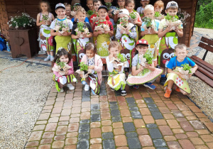 Grupa dzieci 5-6 letnich na tle altany z sadzonkami ziół.